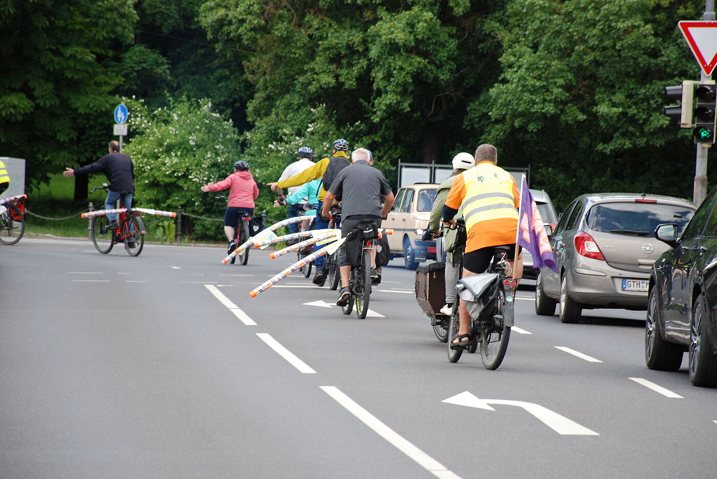 Radfahrende an einer Kreuzung mit Poolnudeln auf den Gepäckträgern zur Kennzeichnung des Mindestüberholabstands von 1,5m.