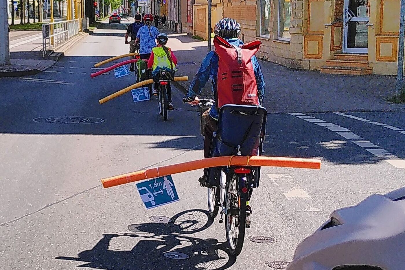 Radfahrer mit Poolnudeln, die den Mindestüberholabstand symbolisieren.