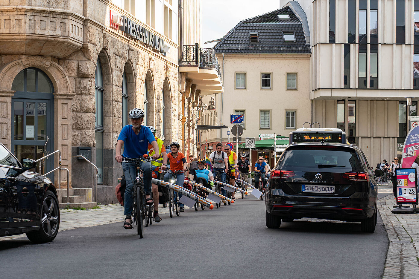 Radfahrer mit Poolnudeln am Gepäckträger fahren durch die Jenaer Innenstadt.